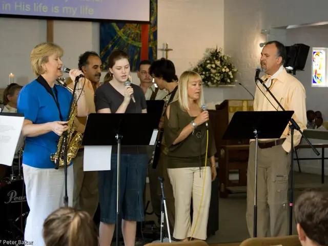 As we can see in the image there is wall, banner, candles, paper, group of people, mics, photo...