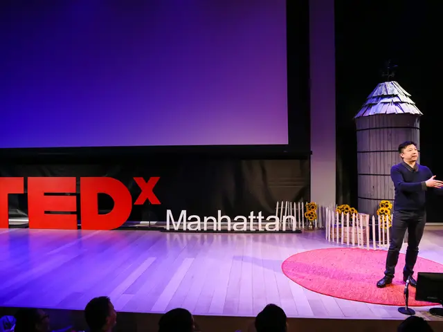 At the bottom of the image there are few people. In front of there is a stage. On the right side of...