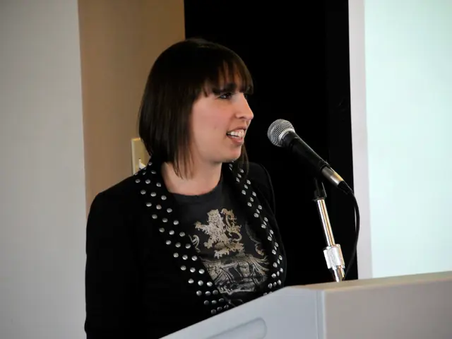 In the center of the image we can see a lady standing, before her there is a podium and a mic. In...